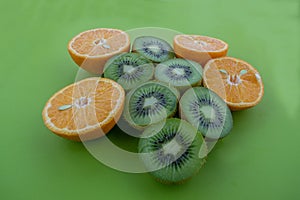 Oranges and kiwis catted on half on green surface
