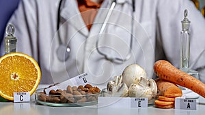 Oranges, mushrooms, nuts and carrots on a laboratory table with the names of vitamins. Essential vitamins. Food