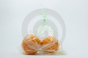 Oranges in a plastic bag on a white background.