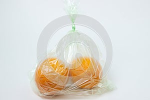 Oranges in a plastic bag on a white background.
