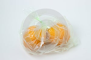 Oranges in a plastic bag on a white background.