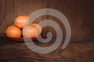 oranges on red plate with wooden background and copy space