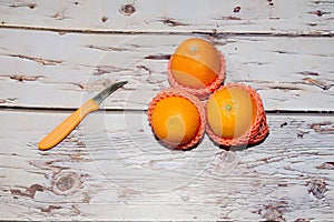 Oranges with a small knife on wooden background