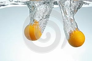 Oranges splashing in water