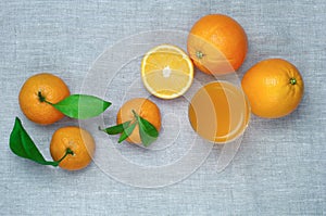 Oranges, tangerines and orange juice in a glass, on a linen tablecloth. Top view.