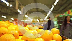 Oranges and unrecognizable customers in supermarket. Slow motion video