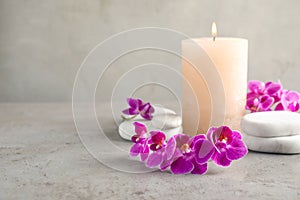 Orchid flowers, spa stones and  on grey table. Space for text