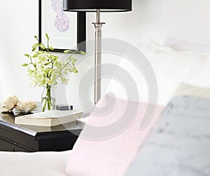 Orchids in vase on pretty bedside table with text space