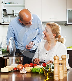 Ordatary mature couple cooking Spaniard tomatoes