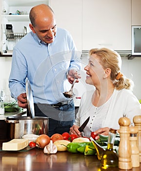 Ordatary mature couple cooking vegetarian soup