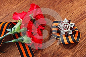 Order of the patriotic war 1st class and two red carnations. Victory Day. 9 May. selective focus image