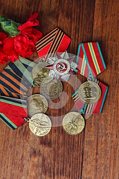 Order of the Patriotic War in St. and Medals for the victory over Germany and two red flower on a table. close up. selective focus