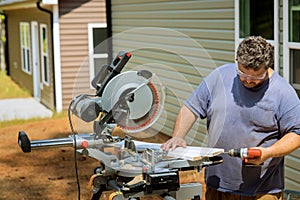 In order to connect wooden boards for construction work, the carpenter is using a screwdriver to drill holes in the