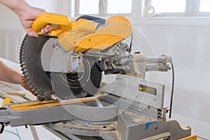 In order to finish the wood moldings and baseboard, a construction worker uses a miter saw to cut