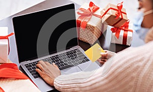 Black lady in mask using laptop and credit card