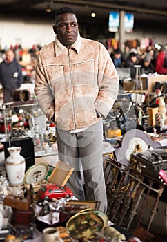 Ordinary afro-american seller in a flea market is waiting for buyers