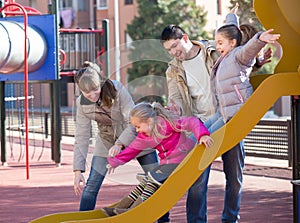 Ordinary family resting at children slide