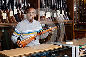 Ordinary gun shop salesman demonstrates combat rifle