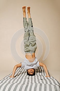 Ordinary indian boy standing on his head on a striped mattress