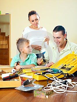 Ordinary nice family of three making something with the working