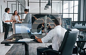 Ordinary office day. Team of stockbrokers works in indoors with many display screens photo