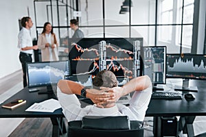 Ordinary office day. Team of stockbrokers works in indoors with many display screens