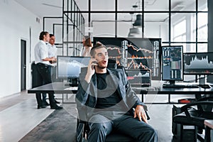 Ordinary office day. Team of stockbrokers works in indoors with many display screens