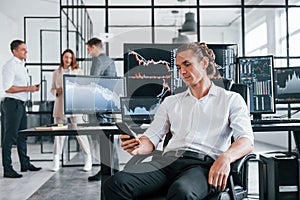 Ordinary office day. Team of stockbrokers works in indoors with many display screens