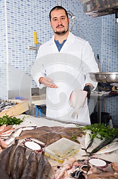 Ordinary salesman in black glove holding fish photo