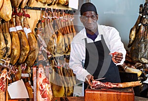 Ordinary seller offering to taste spanish jamon