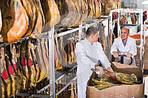 Ordinary smiling positive technologists checking joints of iberico jamon