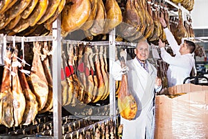 Ordinary smiling technologists checking joints of iberico jamon