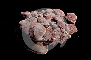 Ore from a diamond mine. isolated on black background with reflexion.