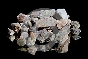 Ore from a diamond mine. isolated on black background with reflexion.