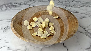 Orecchiette pasta falling into wooden bowl. Marble worktop background