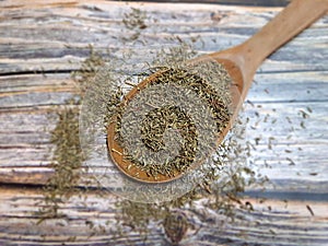 Oregano (Origanum vulgare) dried, dehydrated in a wooden spoon on an old wooden table, top view