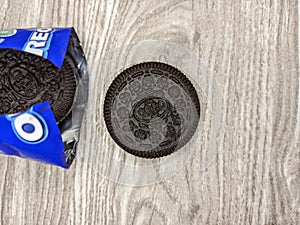 Oreos with open wrap on wood background. It is chocolate sandwich cookies with vanilla flavored cream.