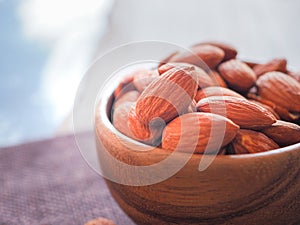 Organic almonds seed in wooden bowl on sackcloth.