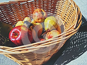 Organic apples, pears and bananas on rustic in a wicker basket