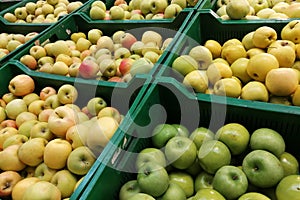 Organic apples in plastic boxes in the supermarket are sorted by varieties. fresh apples store background. Fruits in the pallets