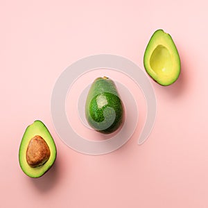 Organic avocado with seed, avocado halves and whole fruits on pink background. Top view. Square crop. Pop art design