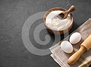 Organic baking ingredients. Flour, eggs and rolling pin on a dark background. Concept of homemade and healthy food