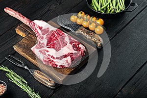 Organic beef meat raw steak,Tomahawk cut, on black wooden table , with copy space for text