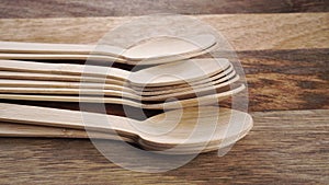 Organic biodegradable bamboo wooden spoons on a textured wood surface.