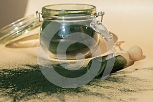Organic blue-green algae spirulina powder food in glass jar with wooden spoon. Health benefits of spirulina chlorella
