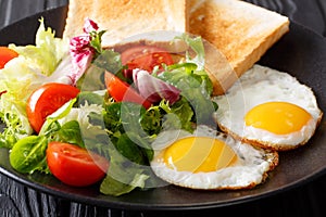 Organic breakfast of fried eggs with fresh salad and toast close