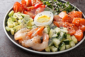 Organic breakfast of salmon, shrimps, eggs and fresh vegetables close-up in a plate. horizontal