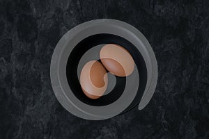 Organic brown raw eggs on black bowl. 3d illustration.