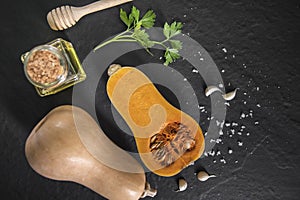 organic butternut squash with spices and ingredients for making on a black slate