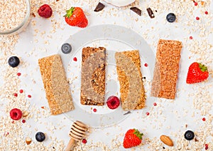 Organic cereal granola bar with berries with honey spoon and jar of oats on marble background. Top view. Strawberry, raspberry and